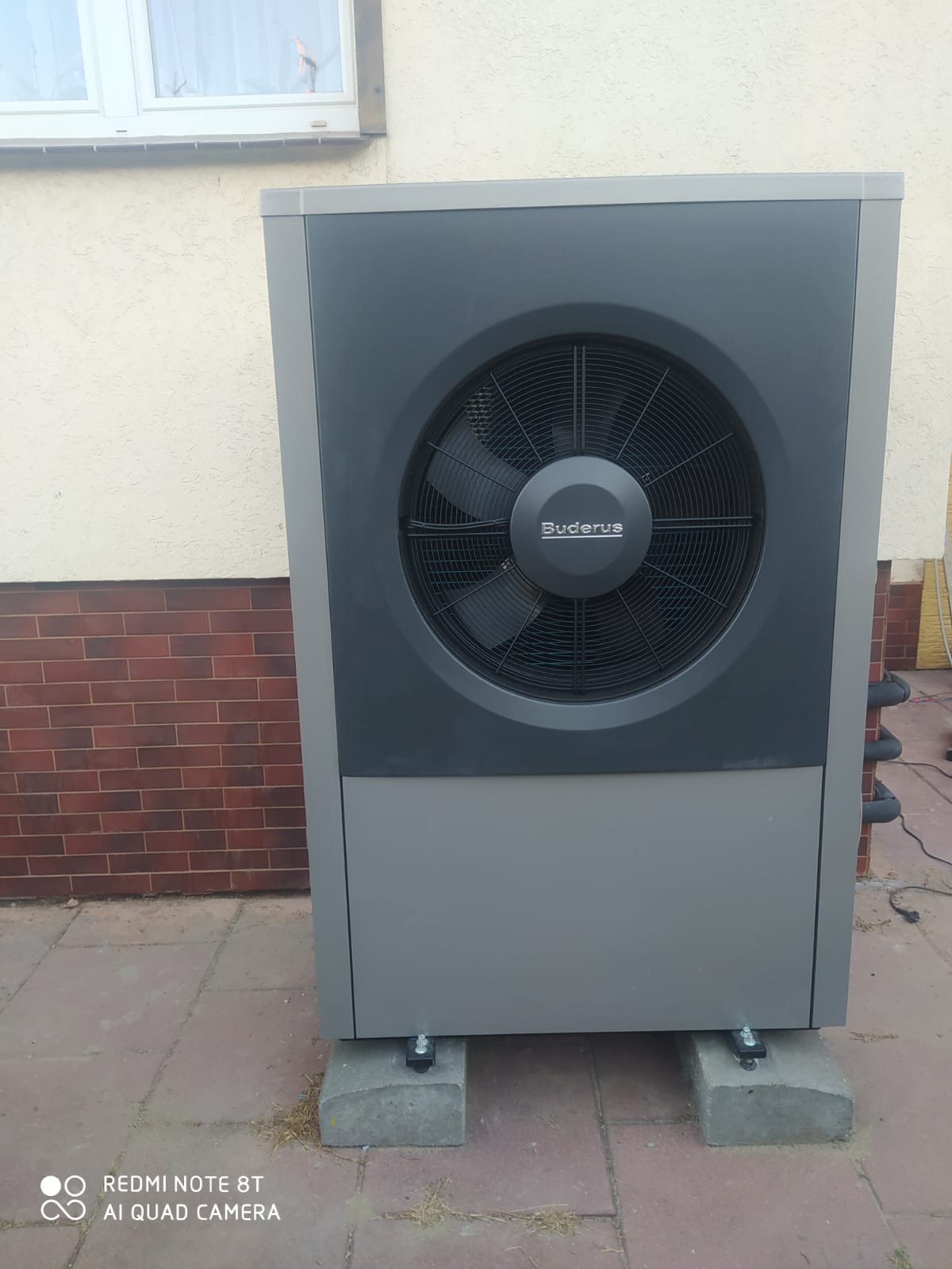 Zewnętrzna jednostka pompy ciepła Buderus zamontowana przy budynku - TOMEX